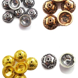 May include: A collection of decorative metal beads in silver, gold, and bronze hues. The beads feature an embossed design with a central hole, and are shown whole and halved. Suitable for jewellery making and crafts.