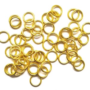 Puede incluir: Una gran cantidad de anillos de salto de color dorado, un tipo de anillo metálico utilizado en la fabricación de joyas.