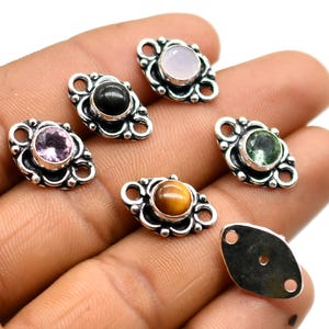 May include: Six silver charm pendants with different colored gemstones. The charms are in the shape of a teardrop with a decorative border. The gemstones are pink, green, black, brown, and white.