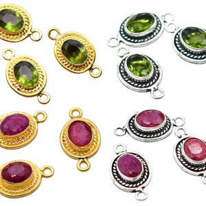 May include: An assortment of gemstone connectors. The connectors feature oval-shaped gemstones in green and red hues, set in gold and silver metal settings. Each connector has loops on either end for attachment.