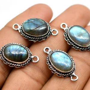 Pode incluir: Quatro pingentes ovais de prata com uma pedra preciosa azul-cinza e dois anéis de salto. Os pingentes têm uma borda prateada decorativa.