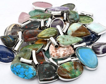 May include: A collection of gemstone pendants in various shapes and colors, including blue, green, red, and purple. Each pendant has a silver-colored metal frame and a loop for a chain. The gemstones have unique patterns and textures.