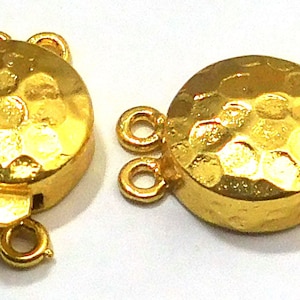May include: Two gold-toned metal clasps with a hammered finish. Each clasp has a round, textured disc and three loops for attaching jewelry.
