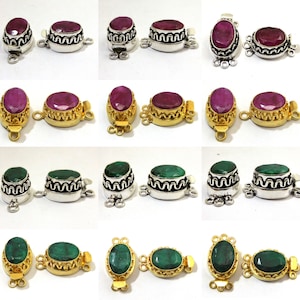 Pode incluir: Dois conjuntos de fechos em tom prateado e dourado com pedras ovais vermelhas e verdes. Os fechos têm um design decorativo em torno da pedra preciosa e três laços para prender a um colar ou pulseira.