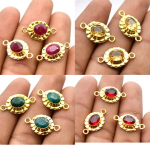 Può includere: Otto ciondoli connettore dorati con pietre preziose di forma ovale. Le pietre preziose sono rosse, gialle e verdi. I ciondoli hanno due anelli su entrambi i lati.