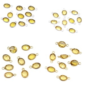 Könnte beinhalten: Mehrere ovale Anhänger aus gelben Edelsteinen mit Schlaufen aus silber- oder goldfarbenem Metall. Die Edelsteine haben ein durchscheinendes Aussehen und sind in Gruppen vor weißem Hintergrund angeordnet. Geeignet für die Schmuckherstellung.