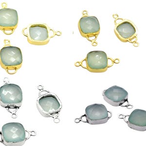Puede incluir: Una colección de conectores de piedras preciosas en engastes dorados y plateados. Las piedras preciosas son de color azul verdoso pálido, de forma cuadrada y facetadas. Los conectores tienen pequeños bucles en cada lado para sujetarlos a otros componentes de joyería.