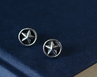 May include: A pair of silver star stud earrings. The earrings are round and have a five-pointed star in the center.
