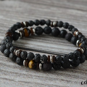 May include: Two-tone bracelet featuring black lava rock beads, tiger's eye beads, and silver spacers.