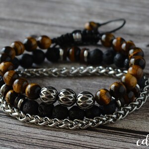 May include: Three layered bracelets featuring tiger's eye beads, black lava beads, and a silver chain.