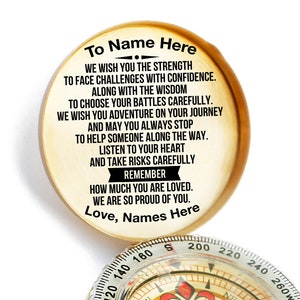 May include: A gold compass with a white face and black needle. The compass is open and the lid has a message that reads "To Name Here We wish you the strength to face challenges with confidence. Along with the wisdom to choose your battles carefully. We wish you adventure on your journey and may you always stop to help someone along the way. Listen to your heart and take risks carefully Remember how much you are loved. We are so proud of you. Love, Names Here"