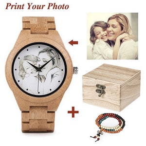 May include: A wooden wristwatch with a white face and a black and white photo of two people printed on it. The watch comes with a wooden box and a beaded bracelet.