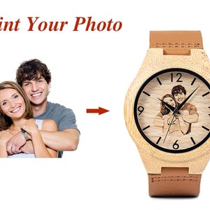 May include: A wooden wristwatch with a brown leather band. The watch face has a black background with white numbers and hands. A photo of a couple is engraved on the watch face. The text "Print Your Photo" is displayed above the watch.
