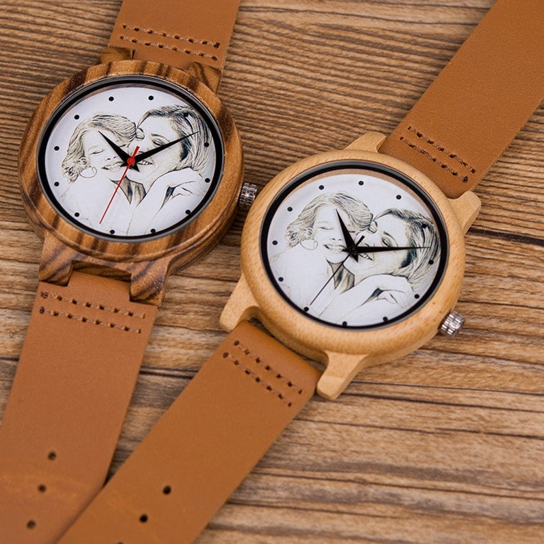 May include: Two wooden wristwatches with brown leather bands. Each watch face features a personalized photo of a mother and daughter embracing.