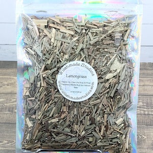 May include: A clear plastic bag filled with dried lemongrass. The bag has a white label with the text "Witchmade Studios Lemongrass Freshen Air Clear the Body & Mind Happiness Repels Bugs but Attracts Bees www.witchmadestudios.com".