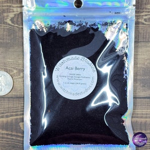 May include: A small resealable bag filled with dark purple freeze-dried acai berry powder. The bag has a white label with the text "Witchmade Studios" and "Acai Berry" in a black circle. The label also includes the text "Freeze Dried", "Shielding Courage, Strength, Purification, Psychic Protection", "1 oz net weight (28.35 grams)", and "www.witchmadestudios.com".