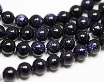 Op de afbeelding: Een streng donkerblauwe ronde kralen met een gespikkelde, glinsterende afwerking. De kralen zijn aan elkaar geregen op een doorzichtige draad.