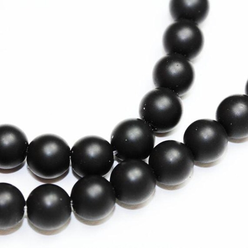 May include: A strand of black matte round beads. The beads are strung together on a clear thread.