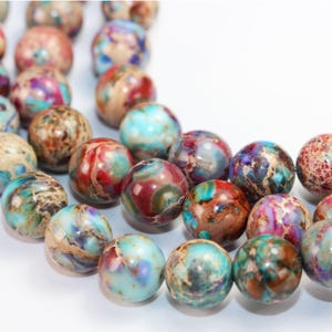 May include: A strand of colourful, round, marbled beads. The beads are a mix of brown, red, blue, and white.