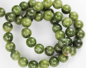 May include: A strand of green jade beads, each bead is round and smooth. The beads are strung on a clear thread.