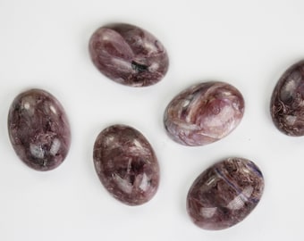 May include: Six oval-shaped purple and white agate stones with a swirling pattern.