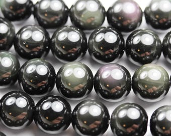 May include: A strand of black obsidian beads with iridescent rainbow flashes. The beads are round and smooth, and they are strung on a clear thread.