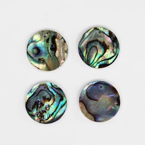 May include: Four round iridescent abalone shell pendants with a hole in the center. The shells have a variety of colors, including green, blue, and brown.