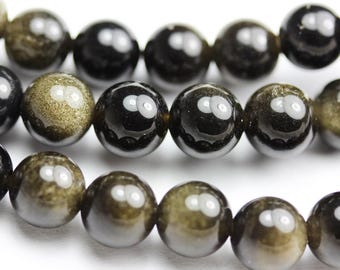 May include: A strand of black and gold beads with a shiny, reflective finish. The beads are round and have a smooth surface.