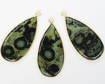 Puede incluir: Tres colgantes en forma de lágrima con un borde dorado. Los colgantes presentan un patrón veteado verde y negro. Cada colgante tiene un pequeño lazo en la parte superior para sujetarlo a una cadena u otro componente de joyería.