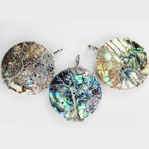 May include: Three round abalone shell pendants featuring silver wire tree designs. The shells are iridescent with shades of brown, green, and blue.