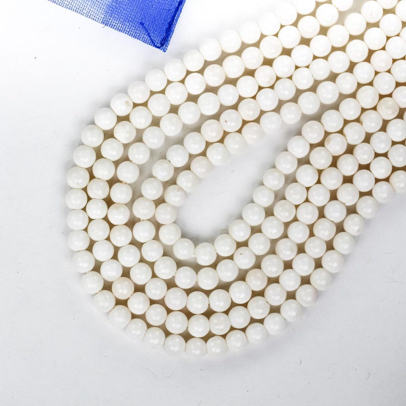 Puede incluir: Una hebra de cuentas redondas blancas hechas de concha natural. Las cuentas est&aacute;n enhebradas en un cord&oacute;n blanco y tienen aproximadamente 6 mm de di&aacute;metro.