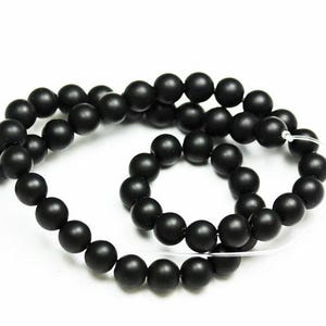 May include: A strand of black matte round beads, strung on a clear elastic cord. The beads are uniform in size and have a smooth, polished finish.