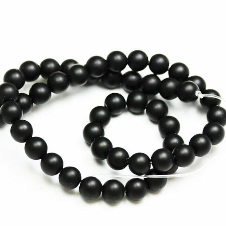 May include: A strand of black matte round beads, strung on a clear elastic cord. The beads are uniform in size and have a smooth, polished finish.