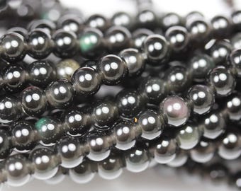 May include: A strand of black obsidian beads with a slight iridescent sheen. The beads are round and smooth, and they are strung together on a clear thread.