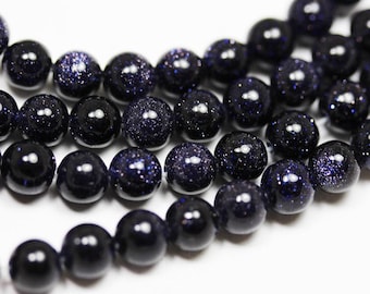Op de afbeelding: Een streng donkerblauwe edelsteen kralen met een gespikkelde, stervormige uitstraling. De kralen zijn rond en glad en zijn aan elkaar geregen op een doorzichtige draad.