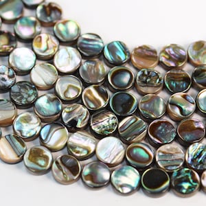 May include: A strand of iridescent abalone shell beads, each bead is round and flat with a smooth, polished surface. The beads are a mix of brown, green, and blue colors with a pearlescent sheen.