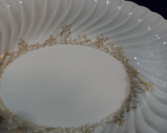 May include: White oval serving dish with a gold rim and a scalloped edge. The rim is decorated with a floral pattern.