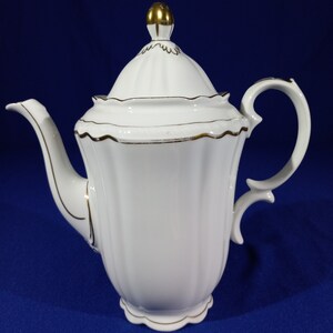 May include: White porcelain coffee pot with a gold trim and a gold knob on the lid.