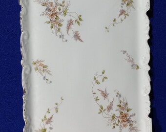 May include: A white porcelain serving tray with a gold rim and delicate floral designs in shades of brown, green, and gray.