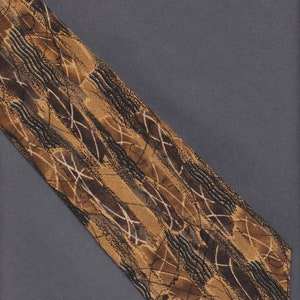 Puede incluir: Una corbata estampada con un diseño de formas y líneas abstractas marrones, beige y negras. La corbata está en ángulo diagonalmente contra un fondo gris. El patrón de la corbata incluye líneas onduladas y líneas blancas que se cruzan.