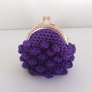 May include: A purple crocheted coin purse with a gold metal clasp.