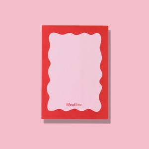 Puede incluir: Un bloc de notas rectangular con un borde rojo y un borde ondulado irregular. El interior es de color rosa claro, con el texto "lifeoflone." en la parte inferior. El bloc de notas está sobre un fondo rosa.
