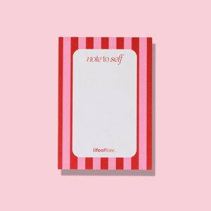 Può includere: Un blocco note rettangolare con interno bianco e bordo a righe rosse e rosa. Il testo "note to self" è in alto al centro e "lifeoflone." in basso. Il blocco note è su uno sfondo rosa.