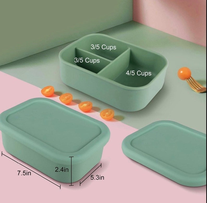 May include: A green silicone food container with three compartments. The compartments are labeled 3/5 cups, 3/5 cups, and 4/5 cups. The container is 7.5 inches long, 5.3 inches wide, and 2.4 inches high.