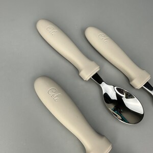 May include: Three white handled utensils with the word "Cole" embossed on the handles. The utensils are a spoon, a knife, and a fork.