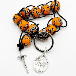 May include: Orange and black beaded rosary keychain with a silver charm featuring Mary, Comfort of the Sick, and the text "Mary, Comfort of the Sick, pray for us".