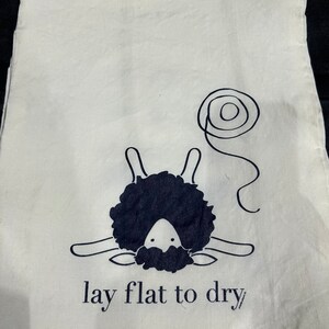 May include: A white cotton drawstring bag with a black sheep illustration and the text "lay flat to dry".