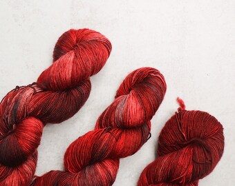 Puede incluir: Tres ovillos de hilo en tonos rojos y burdeos. El hilo es suave y esponjoso, y sería perfecto para tejer o hacer ganchillo.