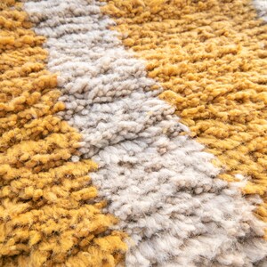 May include: Close-up of a fluffy rug with alternating stripes of mustard yellow and off-white.
