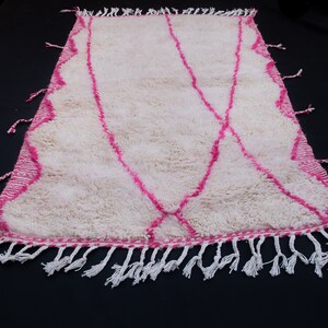 May include: White shag rug with a pink geometric pattern and white fringe.